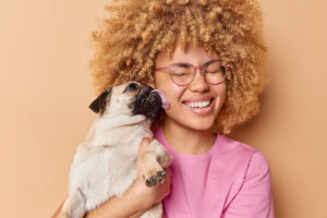 female-owner-holding-pug-as-it-licks-her-cheek